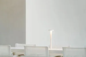 A white dining room with a white table and chairs, surrounded by a clean and minimalist design, with soft and diffused lighting creating a warm atmosphere