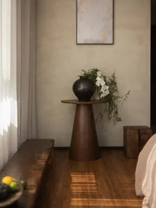一間舒適的客廳隔間，地板是木地板，床、躺椅、玻璃花瓶裝著白色的花，放在桌子上，透過窗戶進入的自然光線