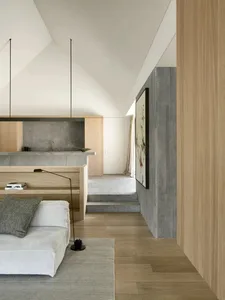 Cozy modern living space with a couch, chair, and dining table, featuring wooden elements and a warm atmosphere