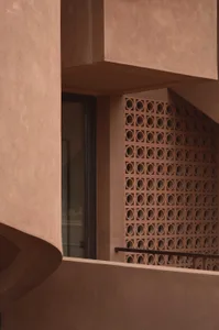 A brown building with a brick exterior, featuring a window with a view of a staircase, set in a natural outdoor environment with dark lighting
