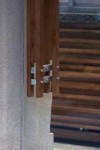 A building with a wooden structure and stone wall, featuring glass panels and a mix of traditional and modern architectural styles, bathed in natural sunlight
