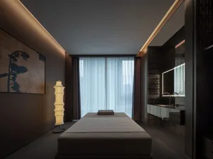 A dimly lit bedroom with a white bed, a wooden bed frame, and a brown window frame, set against a neutral background