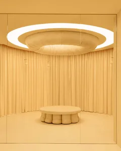Bright and inviting dining space with a cream-colored fabric-covered wall, a large white circular table, and a warm atmosphere