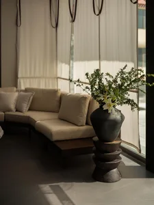 A well-lit living room with a couch and a vase with flowers on a table, creating a comfortable and inviting atmosphere