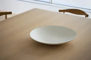 餐廳區域中的木製餐桌上放著一塊白色餐盤