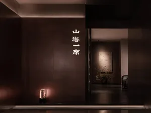 Cozy hallway with a brown wall adorned with Chinese characters, a potted plant, and dim lighting