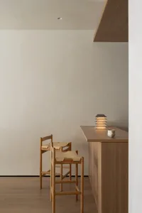 A kitchen or dining area with a wooden counter, chair, and overhead light, featuring a clean and organized space with a focus on functionality and simplicity