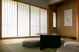 溫馨的客廳或用餐區，木地板搭配黑色餐桌與椅子，擺放抱枕與花瓶，營造溫暖且親切的氛圍