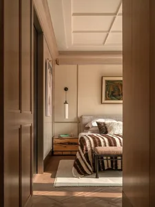 Wooden bedroom with a bed, chair, and couch, warm and cozy atmosphere, natural lighting
