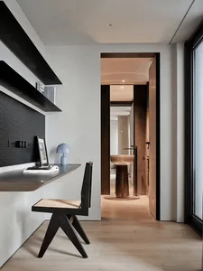 Cozy study with a wooden floor, a desk with a laptop and a book, a sink, and a mirror, lit by dim overhead lighting