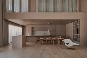 A warm and inviting kitchen and dining area with wooden floors and walls, natural light, and a dining table surrounded by chairs