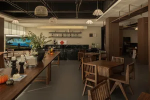 Warm and inviting restaurant with wooden tables, chairs, and a rustic counter with bottles and a sink