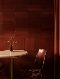 Dining area with a marble table and wooden chairs, surrounded by a brick wall, with a vase and flowers on the table, in a dimly lit space