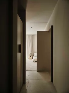 Dimly lit bedroom with a bed, chair, and handbag, creating a cozy atmosphere