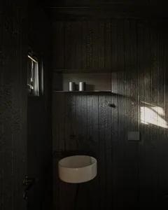 Dimly lit vintage bathroom with a sink, mirror, and window, featuring wooden walls