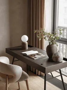 A modern living room with a wooden floor, a dining table, a chair, a potted plant, and a window with natural light