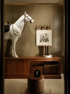 A cozy living room with a horse statue and mounted horse head, wooden cabinet, and brown table, creating a warm atmosphere