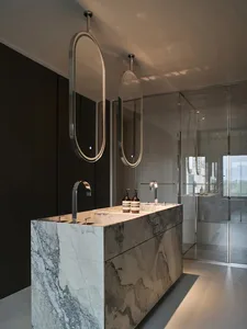 Modern bathroom with a white marble countertop, sink, mirror, and decorative bottles and a cup