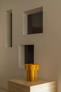 A dimly lit room with a brown wall, a window, and a yellow vase on a table