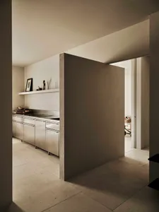 A modern kitchen with a white wall, marble countertop, stainless steel refrigerator, and dining table, lit dimly for a cozy atmosphere