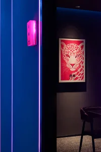 A living room with a leopard print wall, purple lighting, and a chair and couch, creating a visually interesting and stylish space