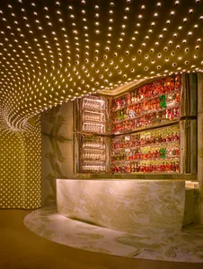 A modern bar with a marble bar and a visually appealing display of liquor bottles, set in a warm and inviting atmosphere