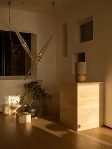 A modern living room with a white color scheme, natural light, and a potted plant, decorated with a vase
