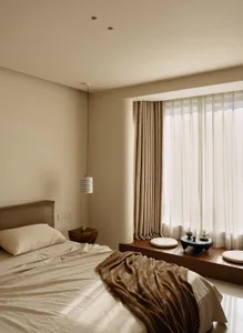 A well-lit bedroom with a bed, window, and table lamp, featuring wood and fabric materials in a warm and inviting space