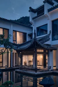 A dimly lit restaurant with a Chinese-style roof and Asian-inspired interior, contrasting white exterior and cozy atmosphere