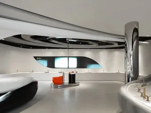 Well-lit living room with a white color scheme, a curved wall with a mounted TV, and comfortable seating options