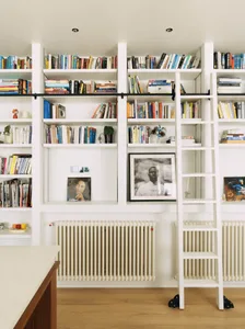 A calm and organized study area with a white bookshelf in the center, filled with books of various sizes and colors