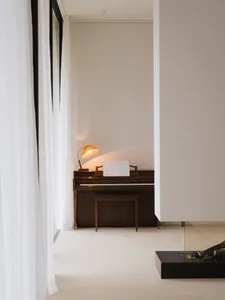 Cozy living space with a piano and fireplace, featuring a white color scheme and a brown piano, with a warm and inviting atmosphere