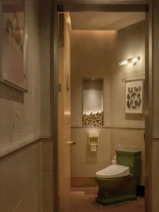 A well-lit bathroom with a green toilet, a sink in the center, and a trash can near the toilet, surrounded by common bathroom materials