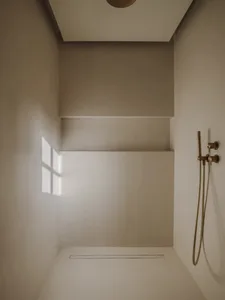 A clean and minimalist bathroom with a white shower and a window above it, letting in natural light