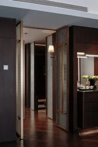 Warm and inviting bedroom with a wooden floor, brown color scheme, and a large mirror on the wall, featuring a table with a vase of flowers and a bed in the background