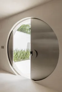 A well-lit modern entrance with a large round metal doorway, surrounded by minimalist design elements