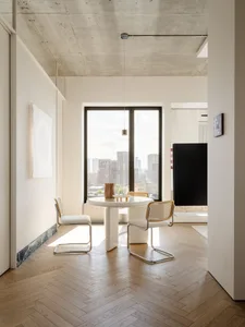 Cozy modern living room with a dining table, chairs, couch, and large window offering a city view