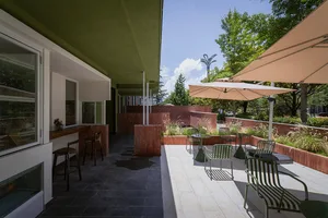 A modern restaurant with a green roof, natural lighting, and comfortable seating areas