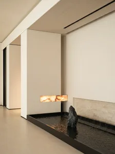 Cozy living space with a stone wall, stone fireplace, and stone floor, dimly lit for a warm atmosphere