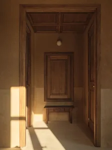A small room with a wooden bench against the wall, a wooden door, and a window letting in natural light