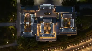 Photograph of a large, multi-story building at night, featuring a mix of architectural styles and modern design elements, with artificial lighting creating a striking contrast against the dark sky