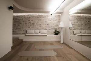 Comfortable living space with a stone wall, a couch, a chair, and a potted plant, well-lit and inviting