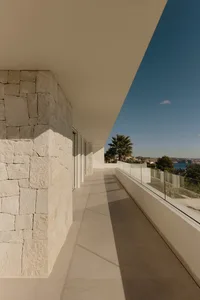 A modern building with a glass balcony, offering a bright and inviting outdoor living area with a serene ocean view