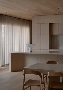 Cozy kitchen with wooden floors, a wooden table, and dim lighting, featuring a sink, refrigerator, and microwave