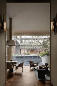 Comfortable living space with a dining table, couch, chair, and large window allowing natural light to fill the room, decorated with a vase, potted plant, and bowl