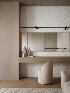 Modern bathroom with stone walls, a sink, chair, and toilet, featuring a large mirror and dim lighting