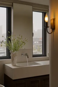 A calm and inviting bathroom with a white sink, a vase of flowers on the counter, and a window behind the flowers