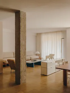 Comfortable living space with a couch, chair, dining table, and rug, lit by natural light from a window