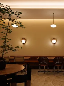A modern dining area with a long wooden table and chairs, a vase, and soft warm lighting