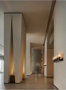 A long and narrow hallway with a white color scheme, patterned walls, and dim lighting, lined with series of lights